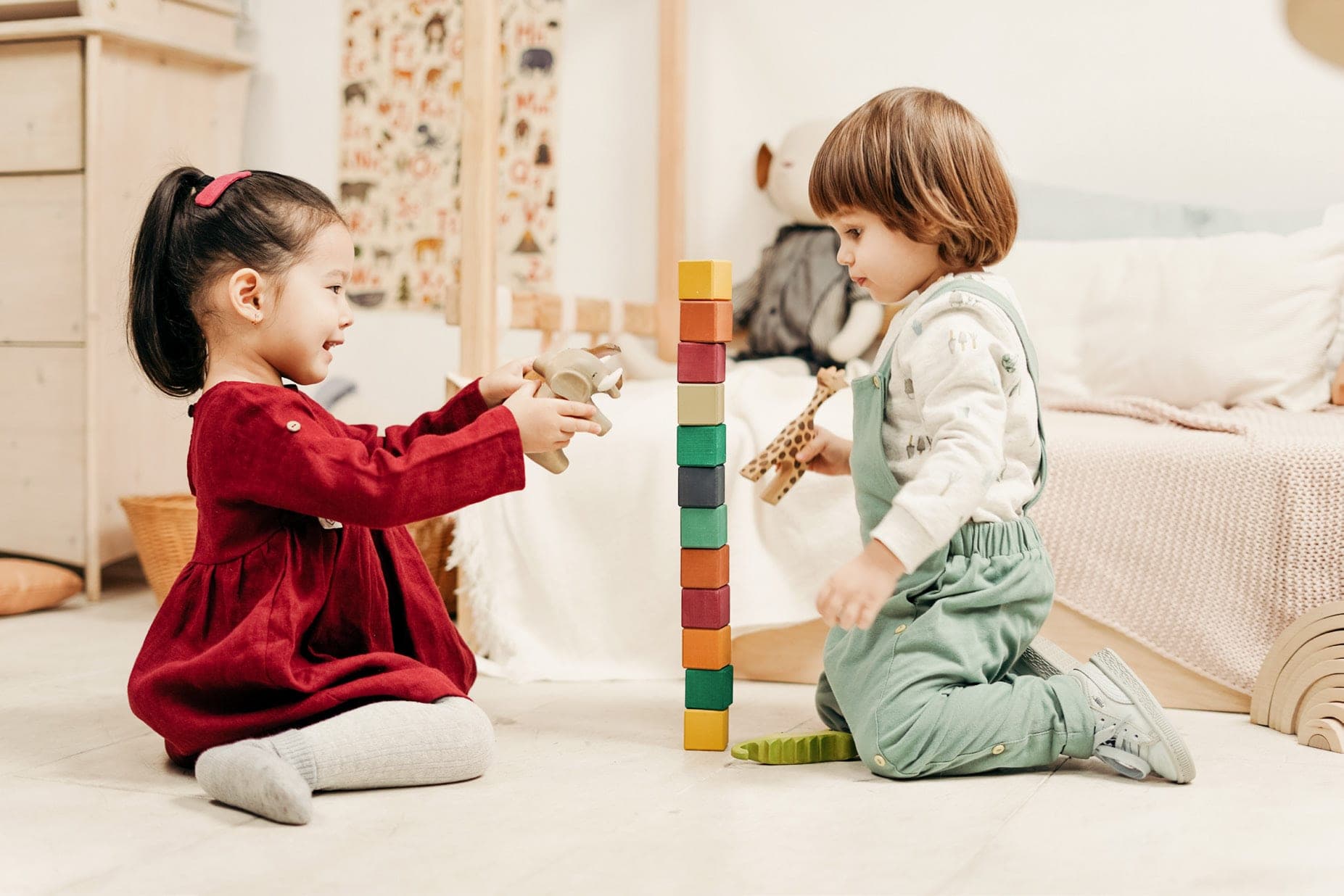 Una niña y un niño construyen una torre de bloques de colores.